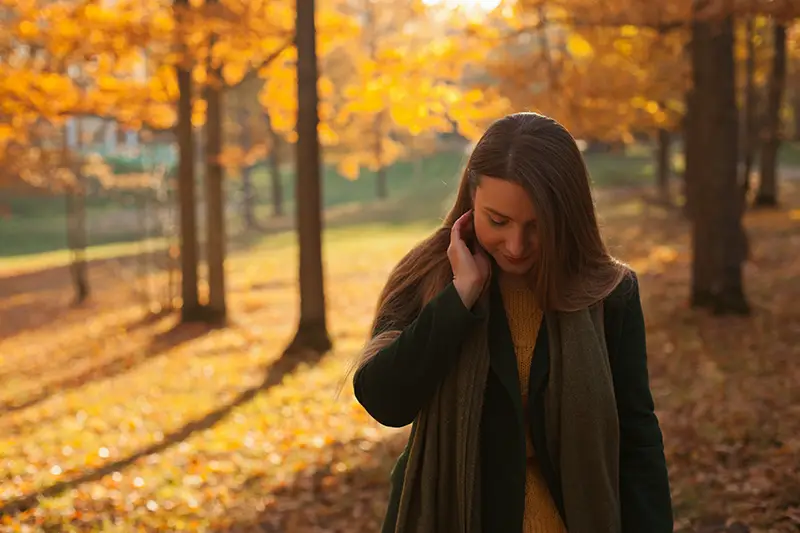 Melancholy woman walking through a park in the fall