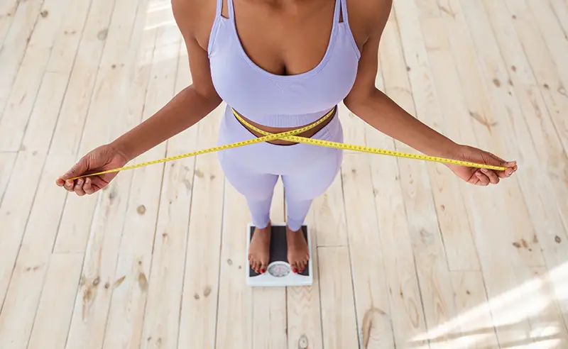 Woman standing with a measuring tape around her waist