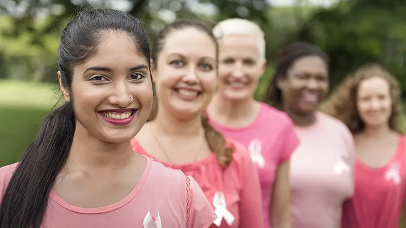 Five women with pinks shirts and cancer ribbons